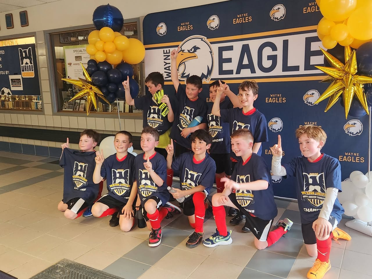 Players celebrating in Wayne United indoor tournament champions shirts