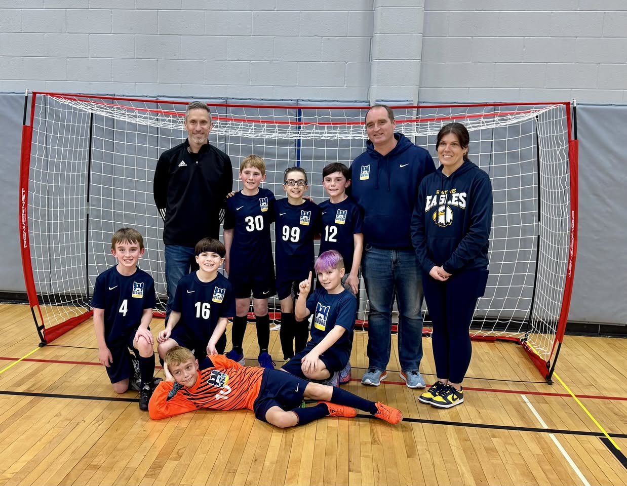 Young Wayne United team lined up by the goal with their coaches